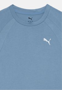 Lyseblå T-skjorte med korte ermer og rund hals, laget av mykt materiale. Har en hvit Puma-logo øverst til venstre.