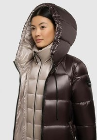 Puffer jacket featuring a glossy dark purple outer layer, large hood, quilted light gray inner lining, and black hardware accents.