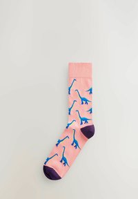Chaussettes roses avec des motifs répétés de dinosaures bleus, présentant un bout violet foncé et un bord côtelé, fabriquées en tissu doux.