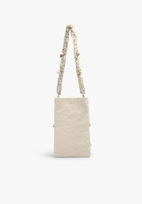 Sac à main en tissu beige de forme rectangulaire. Il présente une sangle texturée ornée de petites coquillages décoratifs et de perles.