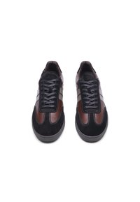 Brown and black low-top sneakers featuring a suede and leather upper, slim white stripes, black laces, and a textured rubber sole.