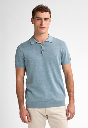 Polo de manga corta azul claro hecho de tejido texturizado, que presenta un collar clásico, tapeta de tres botones y dobladillo acanalado.