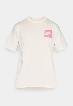 Bela bombažna majica s kvadratnim roza logotipom na prsih. Ima kratke rokave in okrogel izrez na vratu.