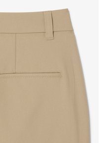 Pantaloni beige con tessuto liscio e strutturato. Presentano una fascia in vita larga, passanti per cintura e una tasca posteriore con filetto singolo.