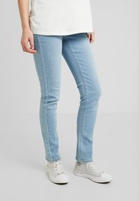 Světle modré úzké džíny z denimu, s přiléhavým střihem, standardním pasem a jemným prošíváním. V kombinaci se světlemi teniskami.