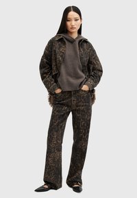 Giacca di jeans con stampa animale marrone e pantaloni a gamba larga abbinati, indossati con un maglione scuro e ballerine nere. Tessuto morbido e vestibilità rilassata.