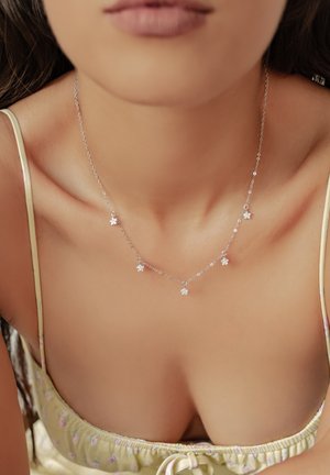 Silberne Kettennacklace mit fünf kleinen Sternen-Anhängern, zartes Design, leicht, auf nackter Haut getragen.