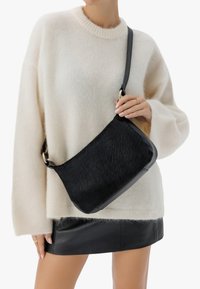 Borsa a spalla in pelle nera e pelliccia texturizzata con una sola tracolla, accessori in oro, forma rettangolare e finitura liscia.