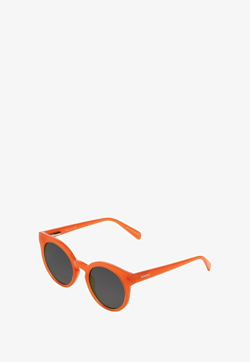 Lunettes de soleil rondes avec une monture orange brillante et des verres sombres. Comprend des branches fines avec une gravure de marque sur la tempête.