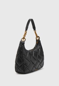 Černá prošívaná kožená kabelka se zlatými řetězovými poutky, koženým ramenním popruhem a horním zipovým uzávěrem na šedém pozadí.