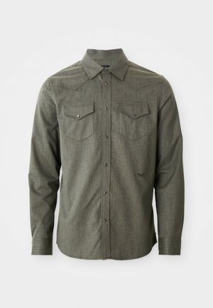 Camisa abotonada de manga larga en verde, hecha de una tela texturizada. Presenta dos bolsillos en el pecho y un collar puntiagudo con detalle de yugo de estilo western.
