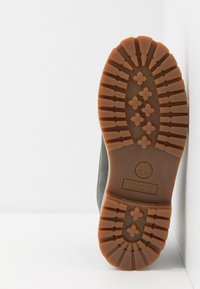 Sole bot Timberland je vyrobena z kvalitní pryže, má vzor s důlky pro přilnavost a je v hnědé barvě s logem.