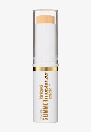 Stick hydratant scintillant teinté Revlon dans un tube blanc avec lettrage doré et un capuchon transparent montrant le bâton de produit beige à l'intérieur.