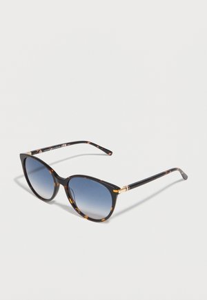 Skildpaddeskjold-formede solbriller med blåtonede gradueringlins og slanke arme, med gyldne accenter nær hængslerne på en hvid baggrund.