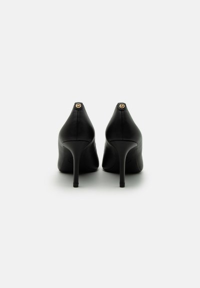 Chaussures à talons hauts en cuir noir avec une pointe effilée et un talon aiguille, arborant un accent de logo doré à l'arrière. Texture lisse, design épuré.