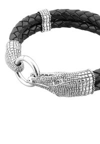 Svart flätad läderarmband med en silverfärgad krokodilhuvudspänne, detaljerade fjäll och en cirkulär metallring för att fästa.