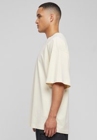 Beige bomull t-skjorte med rund hals, korte ermer og en avslappet passform. Glatt tekstur uten fremtredende mønstre eller detaljer.