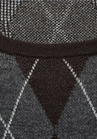 Gros plan d’un tissu tricoté avec un motif losanges gris et brun foncé et un col côtelé à encolure arrondie.