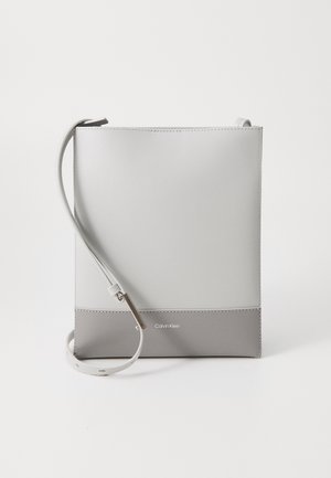 Kleine rechteckige Umhängetasche mit verstellbarem Riemen, hellgrau und dunkelgrauer Farbbereich, Calvin Klein Logo vorne unten in der Mitte.