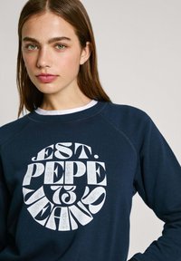 Felpa blu navy con maniche raglan, caratterizzata da un grande design grafico bianco con la scritta "EST. PEPE JEANS." Tessuto morbido e vestibilità casual.