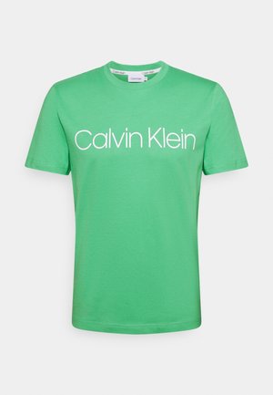 Grøn T-shirt med korte ærmer med hvid "Calvin Klein"-logo centreret på brystet, rund halsudskæring og lige kant.