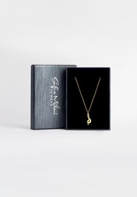 Guldsmykke med en musiknote-pendant præsenteret i en sort velvetforet kasse med et struktureret sølvlåg.