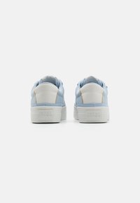 Baskets bleu clair avec des accents blancs, dessus en cuir texturé et épaisse semelle blanche avec logo de la marque embossé au niveau du talon.
