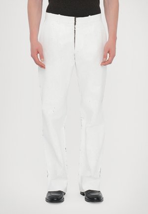 White straight-leg pants with a textured fabric, featuring a zipper and button closure, paired with black dress shoes.