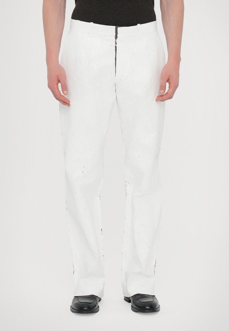 White straight-leg pants with a textured fabric, featuring a zipper and button closure, paired with black dress shoes.