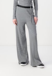 Haut à rayures noir et blanc à manches longues associé à un pantalon large assorti. Comprend une ceinture noire et contraste avec des baskets noires sportives.