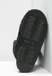 Stivale in suede nero con suola in gomma texturizzata e ondulata. Logo del marchio 'mou' impresso sulla suola. Fodera pelosa visibile lungo il bordo.
