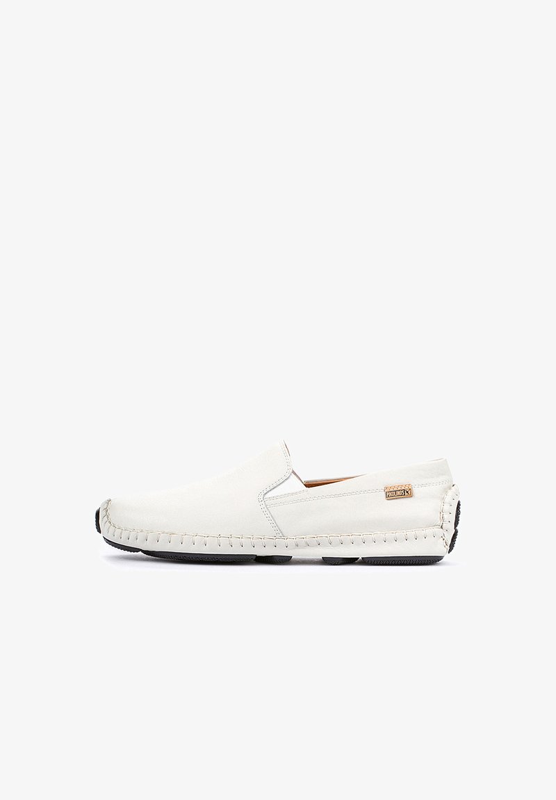 Zapato slip-on de cuero blanco con acentos de costura, puntera redonda, suela de goma negra y una pequeña etiqueta de marca en el lado.