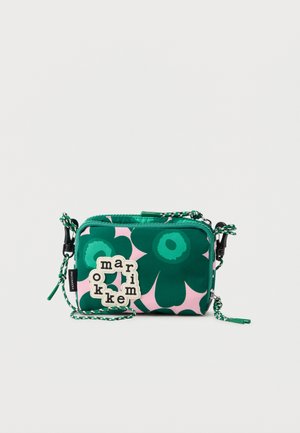 Kicsi téglalap alakú válltáska zöld virágmintával, rózsaszín alapon, fehér logófolttal fekete betűkkel és fonott pánttal.