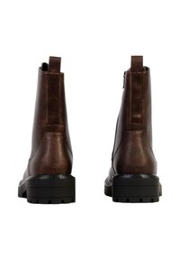 Paire de bottines en cuir marron foncé avec semelles en caoutchouc noires épaisses, vues de dos, sur un fond blanc.