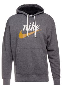 Grå hoodie med en stor vit "nike" logotyp och swoosh i gult. Den har en ficka fram, dragsko på huvan och ribbade muddar och nederkant.