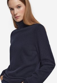 Marinblå polotröja i mjukt material med figurnära design, långärmad och med subtil textur.