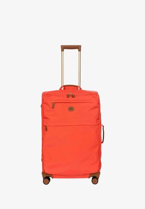 Grande valise souple orange avec poignée rétractable marron, poche avant zippée, poignée latérale et quatre roulettes pivotantes.