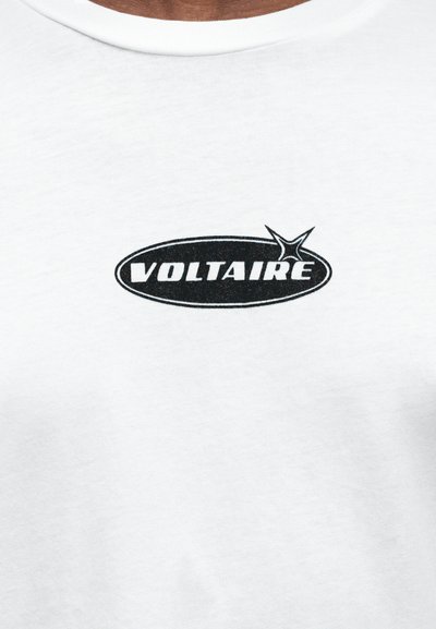 Bílé bavlněné tričko s černým oválným logem s nápisem "VOLTAIRE", doplněné grafikou hvězdy na pravé straně.