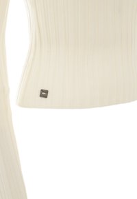 Helles cremefarbenes, geripptes Oberteil mit tailliertem Design, das ein kleines metallisches Etikett am Saum aufweist. Die Textur ist glatt und der Stoff wirkt weich.