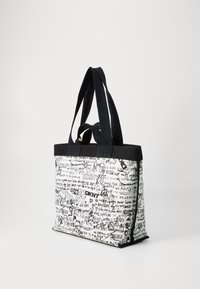 Plátená taška s čiernymi plátkovými popruhmi, s bielym telom pokrytým čiernym textom a kresbami v graffiti štýle, vrátane "DKNY" a rôznych fráz.