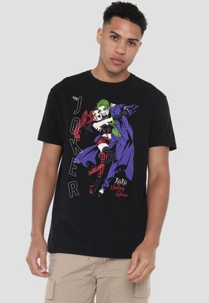Man wearing black t-shirt featuring Joker and Harley Quinn dancing, with text "The Joker" and "xoxo, Harley Quinn" in colorful comic style.