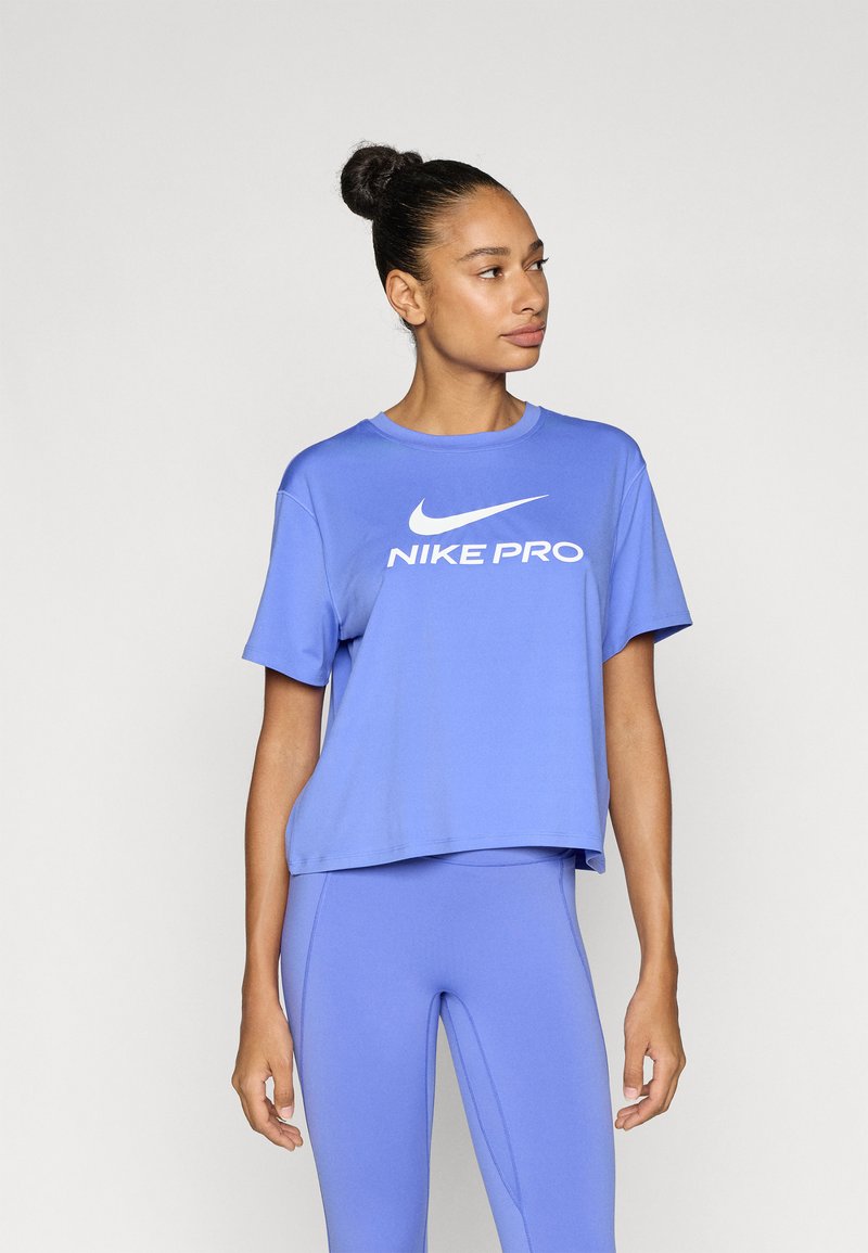 Μωβ crop top Nike Pro με κοντά μανίκια, διακοσμημένο με λευκό λογότυπο μπροστά. Συνδυάζεται με μοβ κολάν που ταιριάζουν. Λείο, αθλητικό ύφασμα.