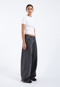 White fitted t-shirt paired with wide-leg gray denim jeans. The jeans feature a faded texture and a high waist with five-pocket design.