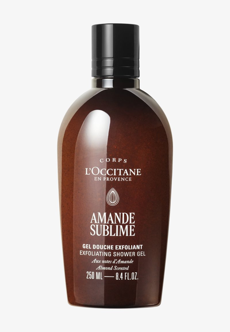 Bottiglia marrone di gel doccia esfoliante L'Occitane Amande Sublime profumato alle mandorle, 250 ml con tappo nero su sfondo bianco.