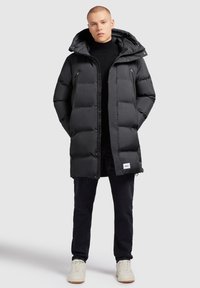 Must must isegi kapuutsiga, millel on ees lukuga kinnitatud, kaks taskut ja veidi kitsam siluett. Kombineeritud tumedate teksade ja heledate kingadega.