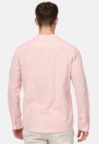 Camicia a maniche lunghe con motivo a righe rosa chiaro e bianche. Presenta polsini con bottoni e orlo dritto. Realizzata in tessuto morbido.