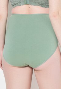 Hoge taille slip van zacht, saliegroen materiaal. Glad textuur met minimale naden en contrasterende taillebanddetails.