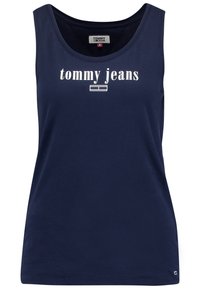Mörkblå bomullstopp utan ärmar med rundad halsringning och vit "tommy jeans"-logotyp. Slät yta och ärmlös design. Har ett litet varumärkesemblem vid fållen.