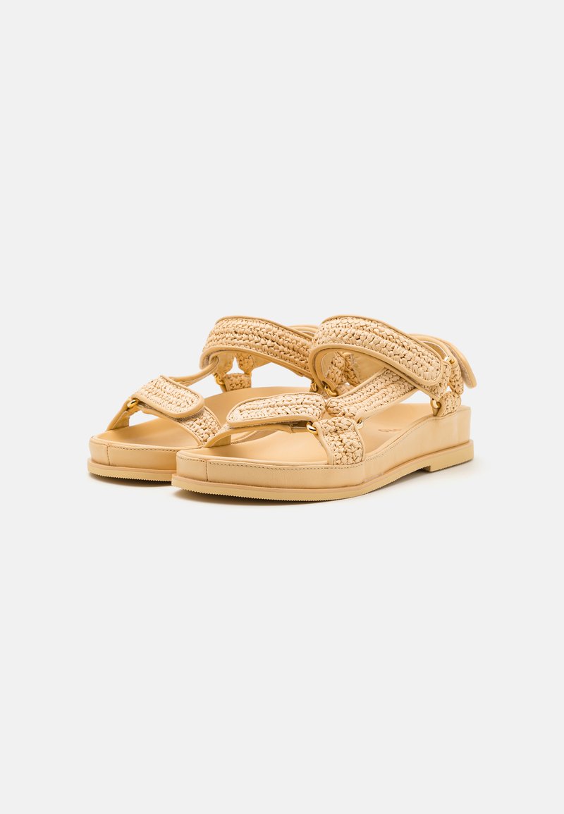Beige Sandalen mit geflochtenen Riemen, flacher Sohle und glatter Oberfläche. Verfügt über ein Zehenstegdesign mit verstellbaren Verschlüssen für einen sicheren Sitz.