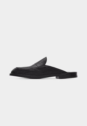 Black leather backless loafer with a low heel and rounded toe, displayed against a plain light background.